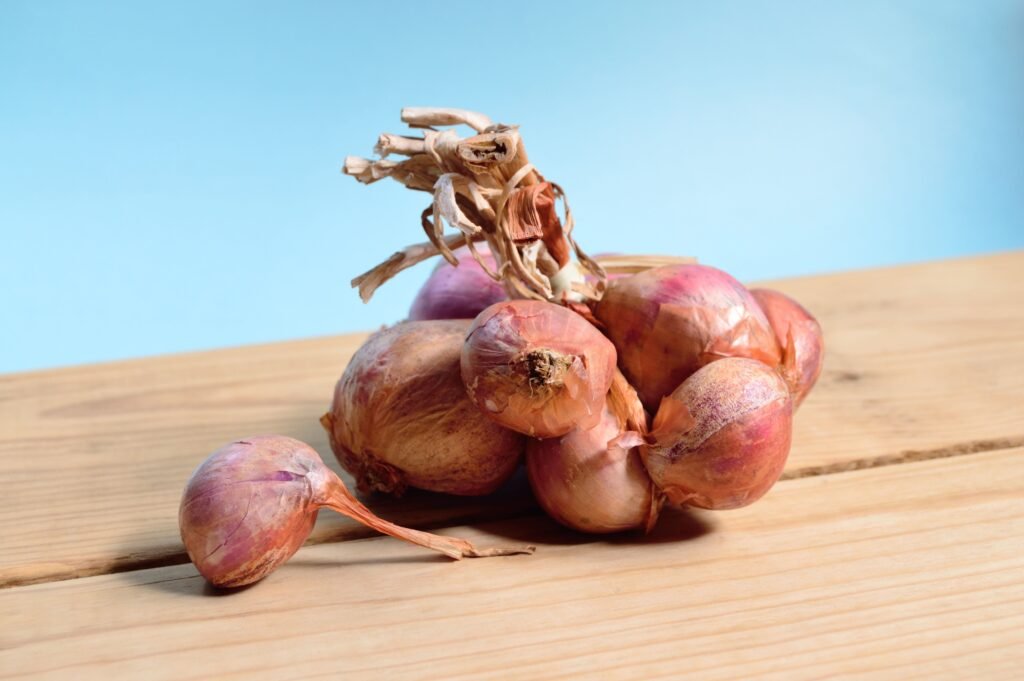 Close-up of fresh shallots on a wooden table against a blue background.
